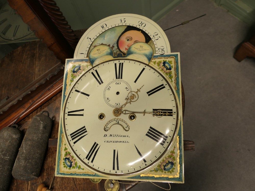 A Georgian mahogany longcase clock with a painted moonphase dial, twisted side columns, brass finials, and flame mahogany inlaid casing. View IV