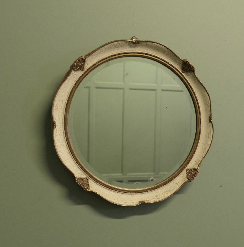 A circular wall mirror featuring a crackle-glazed cream painted frame accented with gilt embellishments and a bevelled glass plate. View III