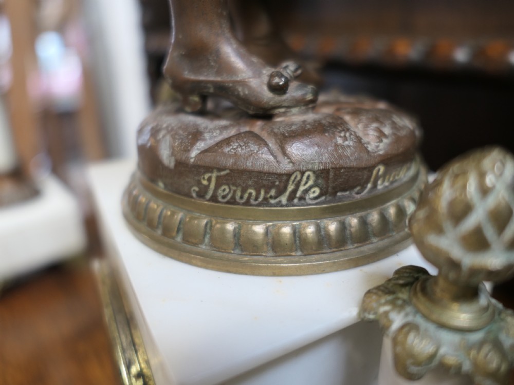 A nineteenth-century French clock garniture set comprising a central bronze sculpture on a marble clock base flanked by two matching multi-arm bronze candelabras. View II
