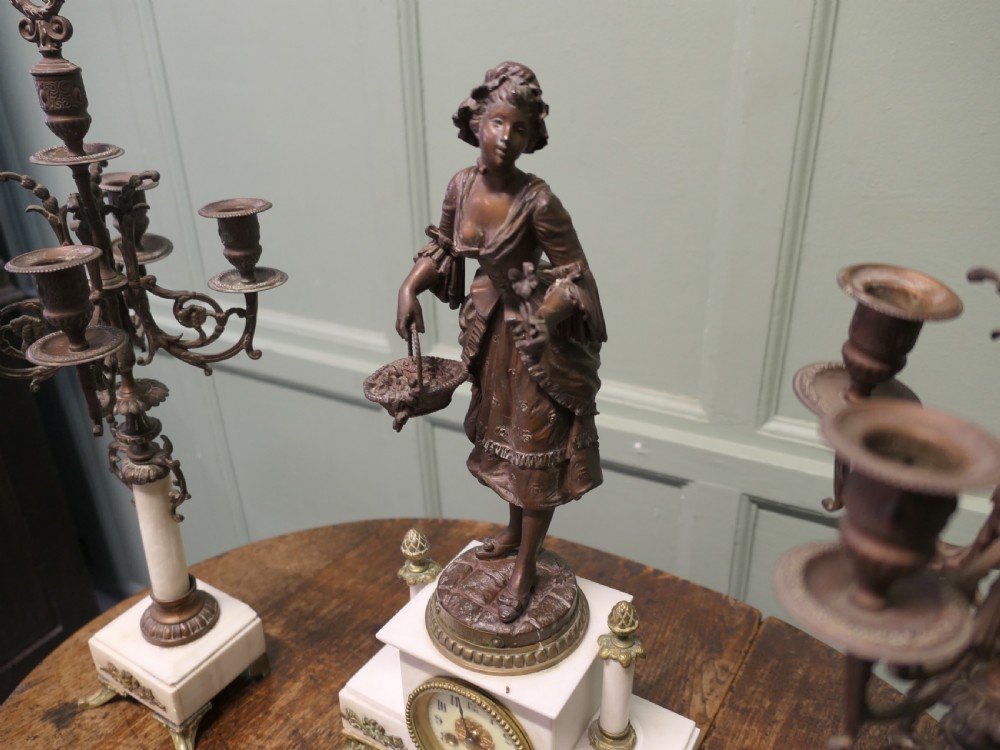 A nineteenth-century French clock garniture set comprising a central bronze sculpture on a marble clock base flanked by two matching multi-arm bronze candelabras. View IV