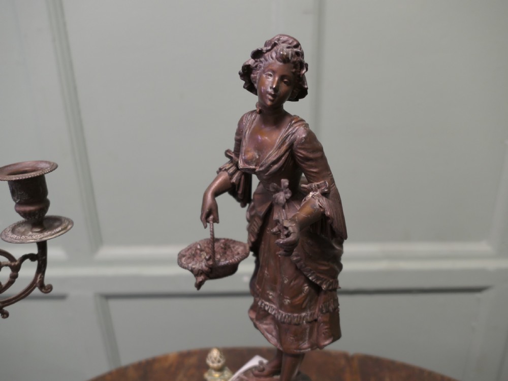 A nineteenth-century French clock garniture set comprising a central bronze sculpture on a marble clock base flanked by two matching multi-arm bronze candelabras. View V