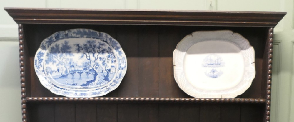 Pair of early nineteenth-century oval earthenware chargers featuring blue and white printed landscape and maritime motifs.