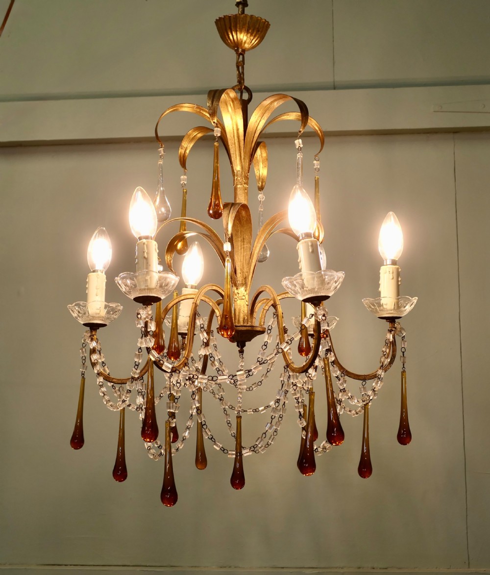 A French gilt metal toleware chandelier featuring curved foliage branches, candle-style bulb holders, clear beaded swags, and suspended amber glass teardrops.