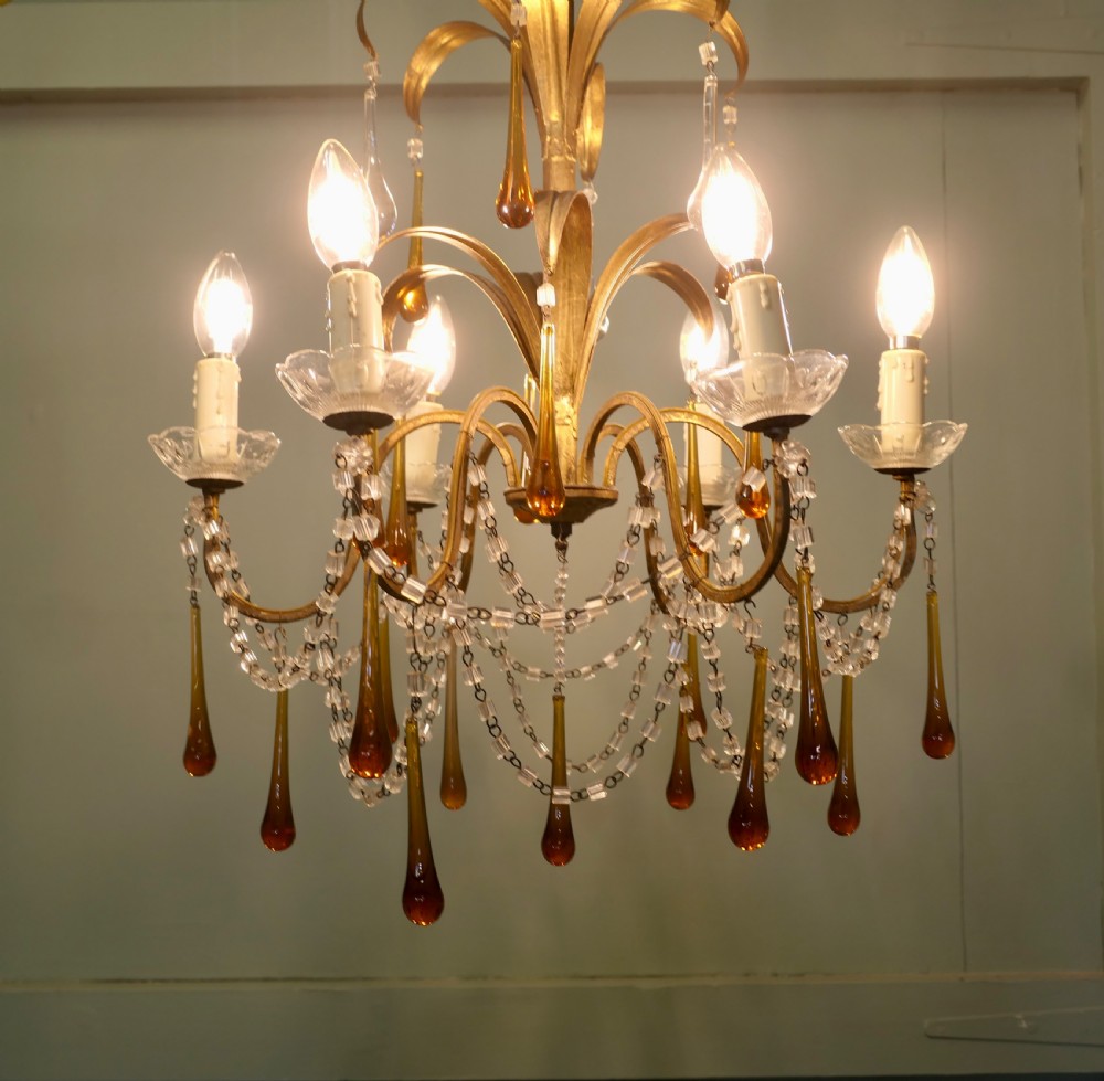 A French gilt metal toleware chandelier featuring curved foliage branches, candle-style bulb holders, clear beaded swags, and suspended amber glass teardrops. View IV