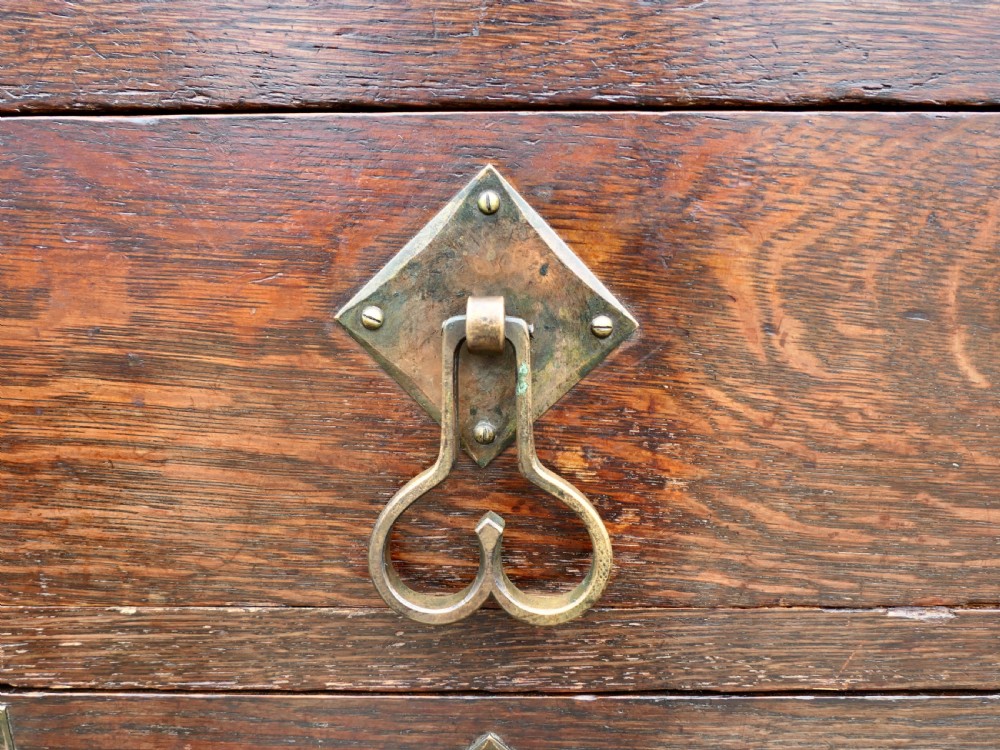 An Arts and Crafts oak sideboard featuring decorative copper strap hinges, heart-shaped drawer pulls, and a low shelf upper gallery. View V