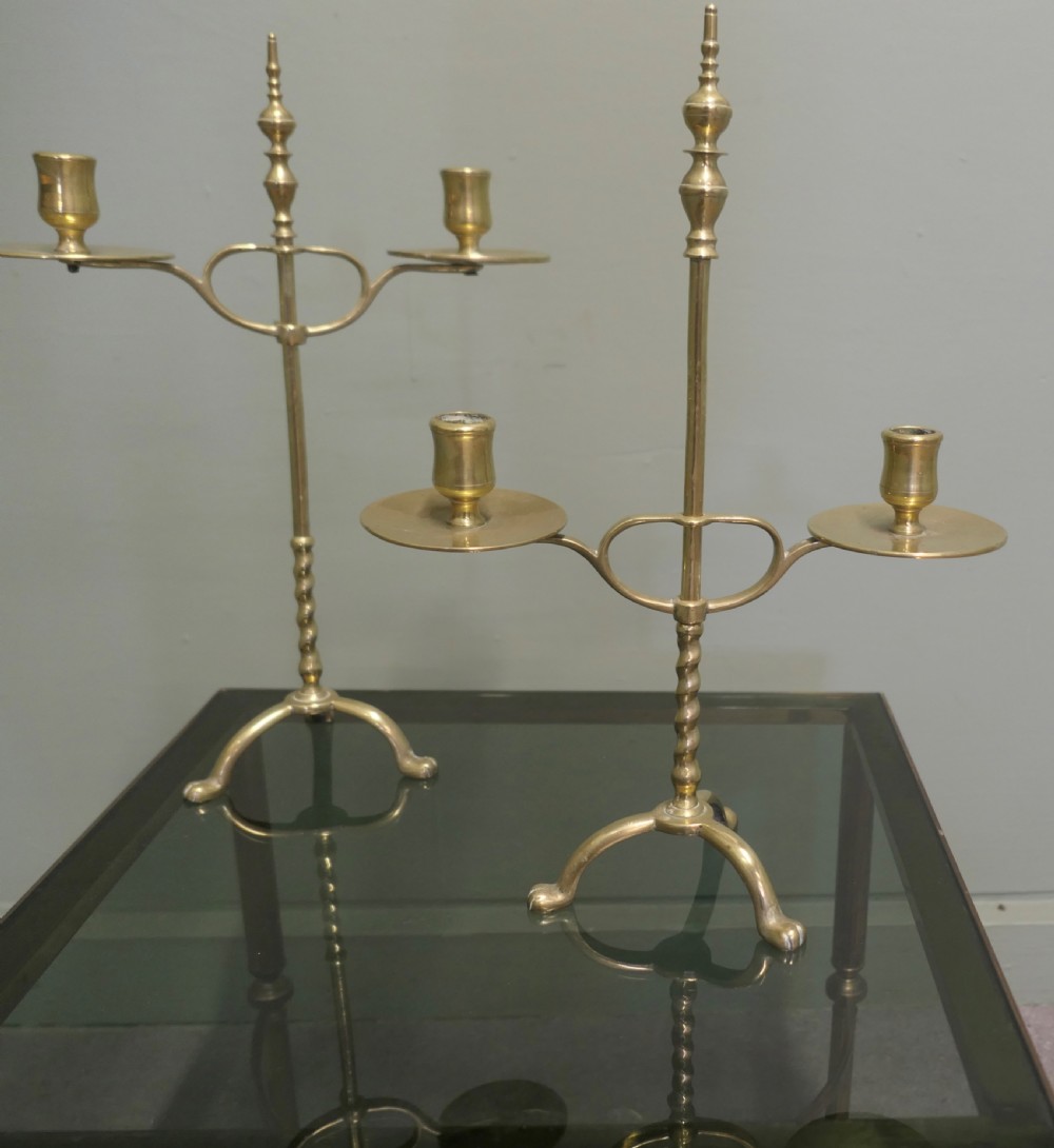 A pair of Arts and Crafts brass student lights featuring adjustable twin candle arms on twisted stems with tripod bases.