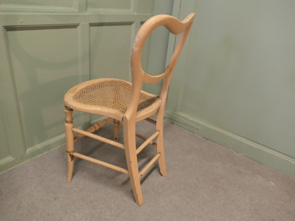 A Victorian painted balloon back bedroom chair featuring a cream frame with hand-painted floral motifs and a woven cane seat. View III