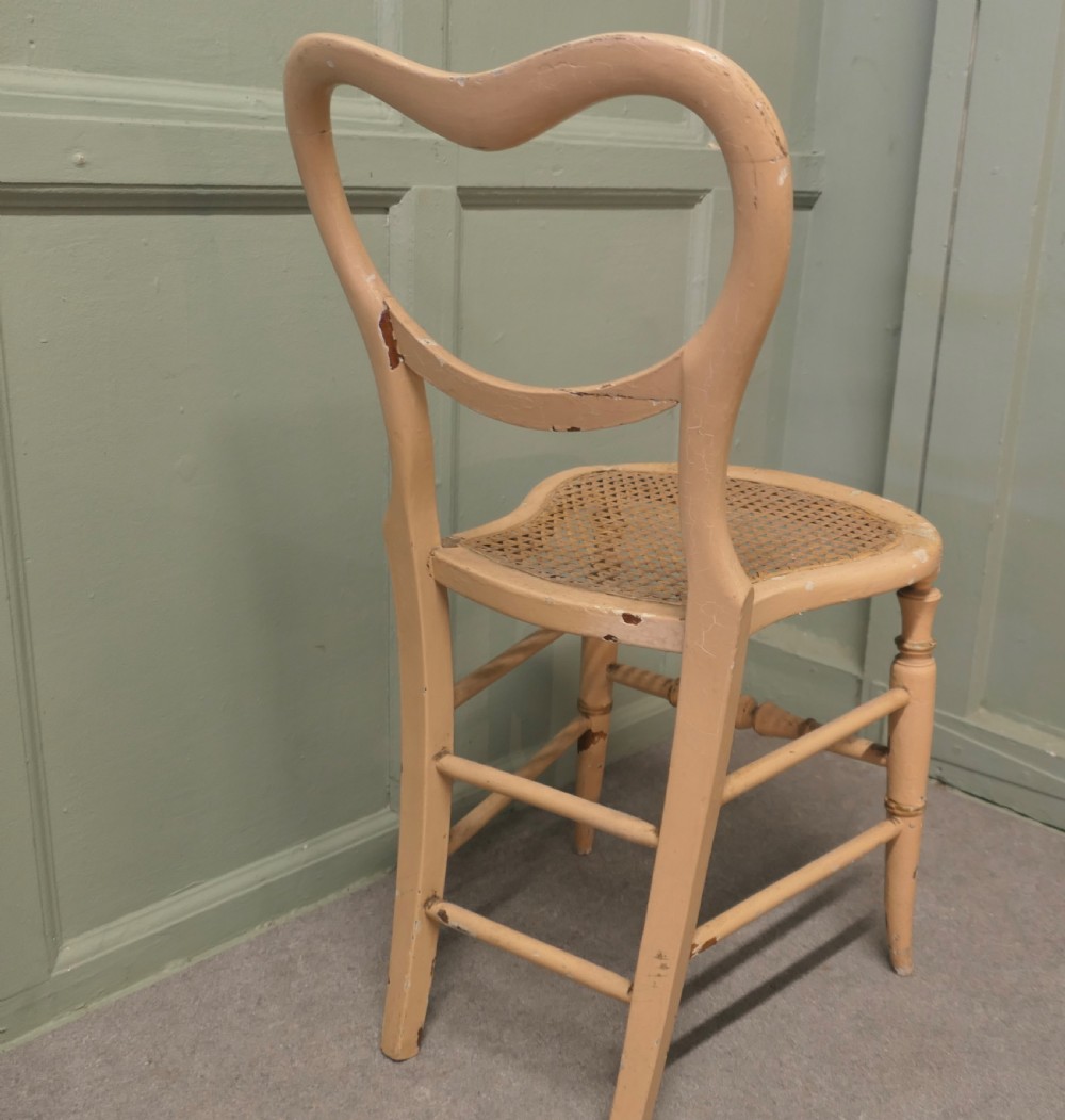 A Victorian painted balloon back bedroom chair featuring a cream frame with hand-painted floral motifs and a woven cane seat. View V