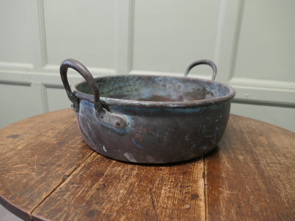 A large 19th-century copper preserving pan featuring twin riveted handles and a patinated finish with hints of verdigris.