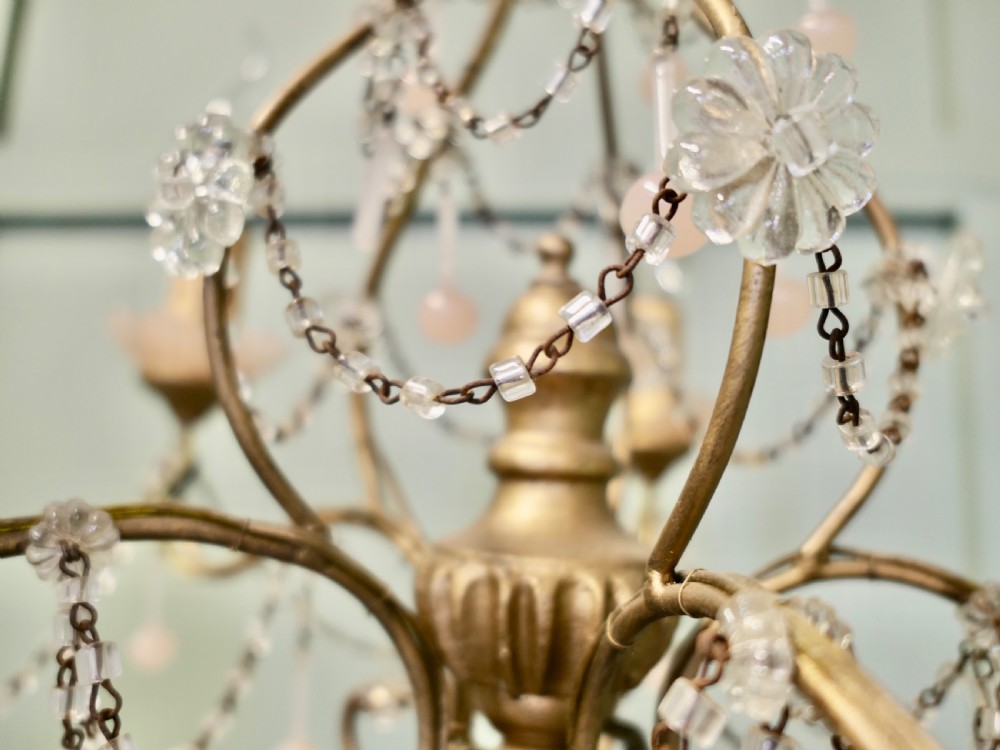 A six-arm gilt metal chandelier featuring frosted floral sconces, hanging pink glass droplets, and delicate beaded crystal swags. View II