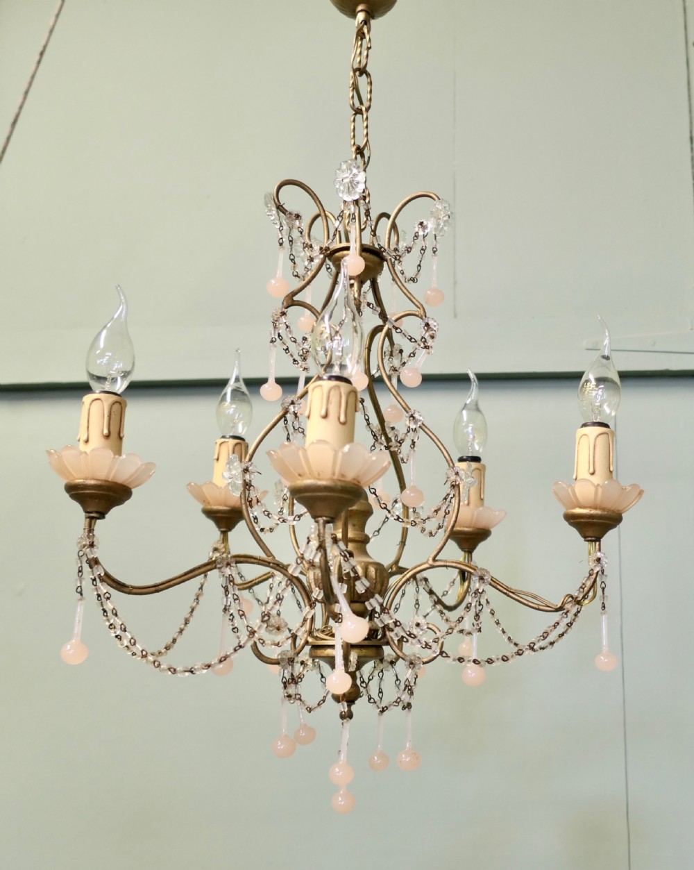 A six-arm gilt metal chandelier featuring frosted floral sconces, hanging pink glass droplets, and delicate beaded crystal swags. View III