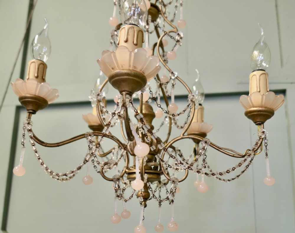 A six-arm gilt metal chandelier featuring frosted floral sconces, hanging pink glass droplets, and delicate beaded crystal swags. View IV