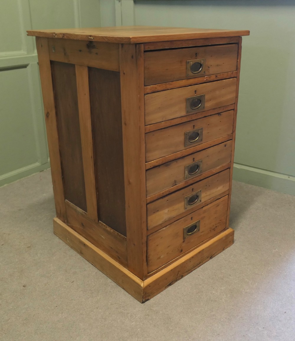 A tall 19th-century pine filing cabinet featuring six shallow drawers with flush brass handles and keyhole escutcheons on a solid plinth base. View III