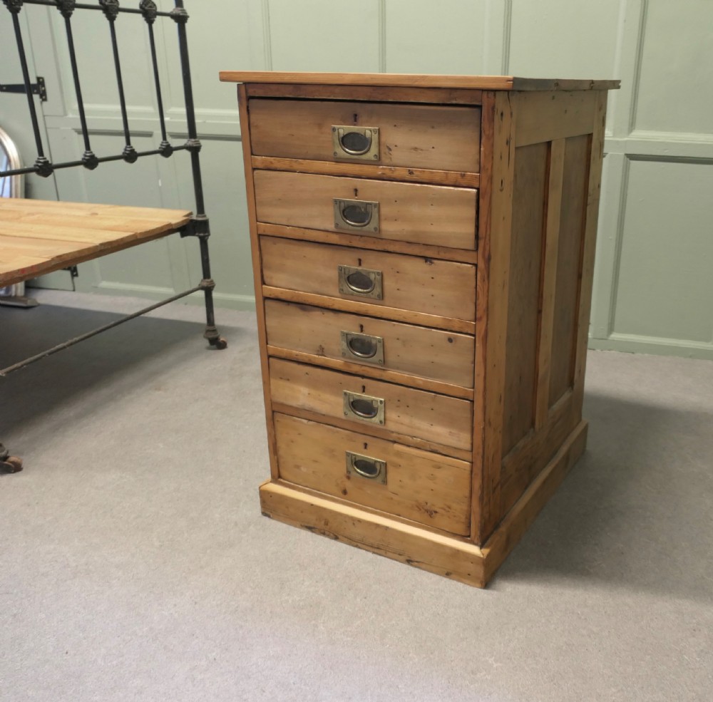 A tall 19th-century pine filing cabinet featuring six shallow drawers with flush brass handles and keyhole escutcheons on a solid plinth base. View IV