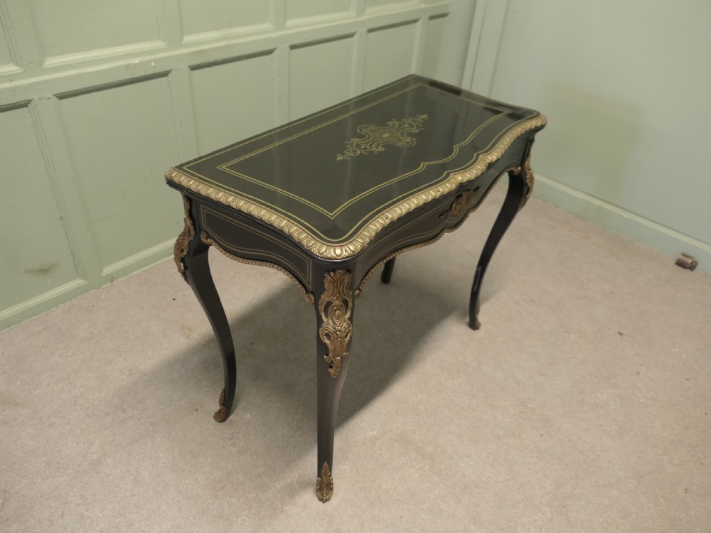 A French Louis XV style ebonised games table featuring brass inlay, decorative ormolu mounts, and slender cabriole legs.