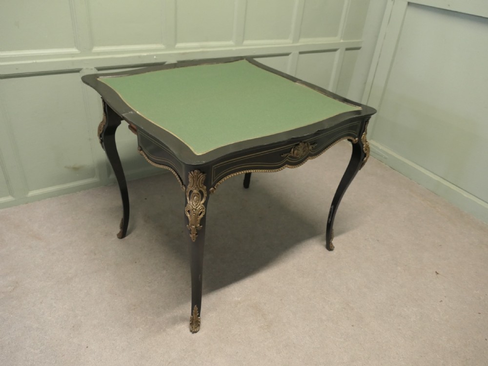 A French Louis XV style ebonised games table featuring brass inlay, decorative ormolu mounts, and slender cabriole legs. View IV
