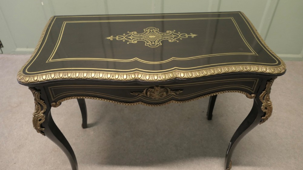 A French Louis XV style ebonised games table featuring brass inlay, decorative ormolu mounts, and slender cabriole legs. View V