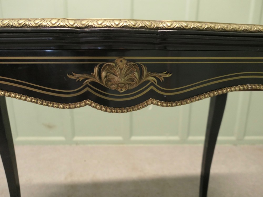 A French Louis XV style ebonised games table featuring brass inlay, decorative ormolu mounts, and slender cabriole legs. View VII