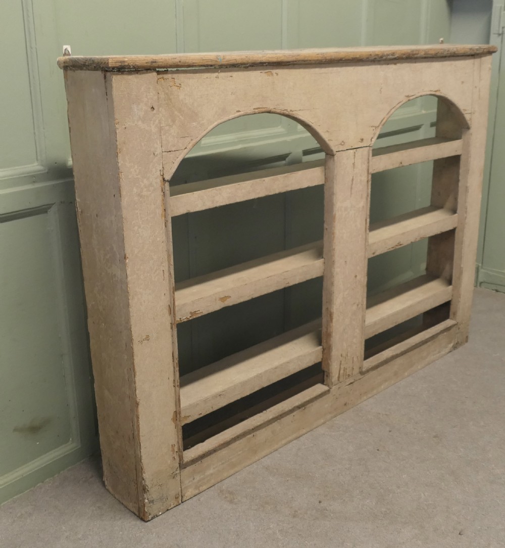 An early 19th-century French pine alcove shelving unit featuring two arched open bays, horizontal interior shelves, and a distressed cream painted finish. View II