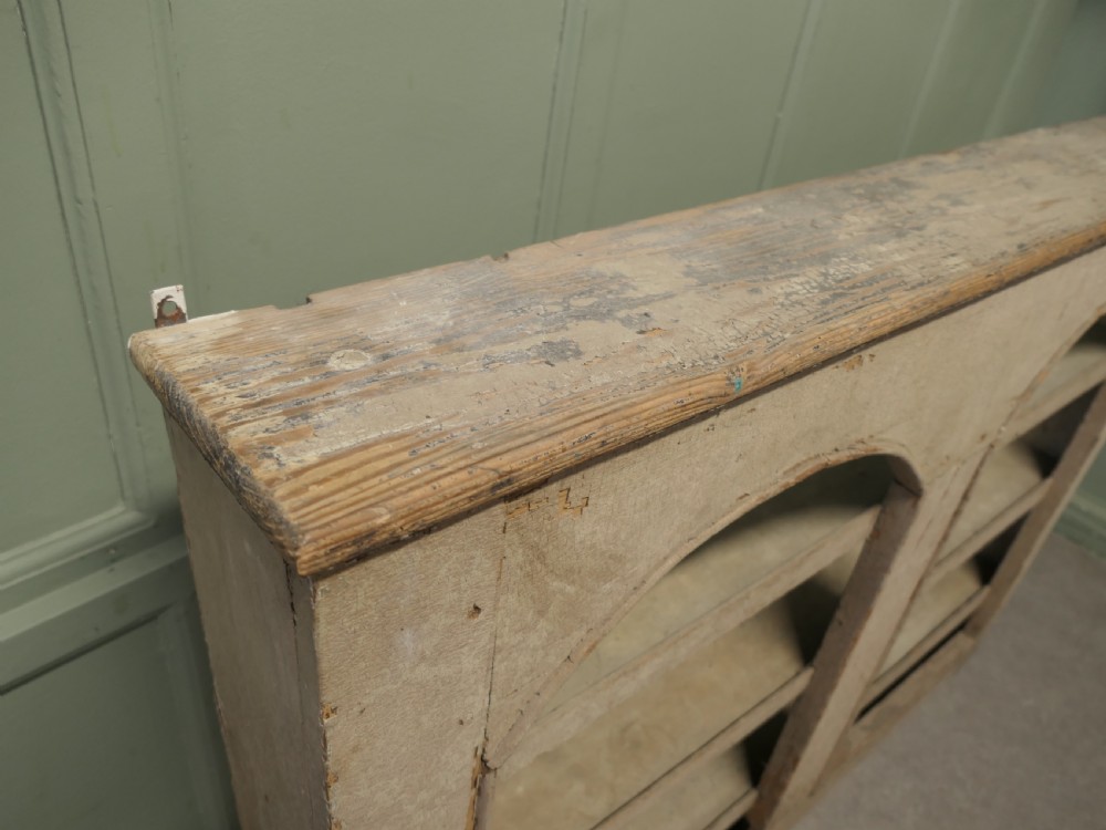 An early 19th-century French pine alcove shelving unit featuring two arched open bays, horizontal interior shelves, and a distressed cream painted finish. View VI