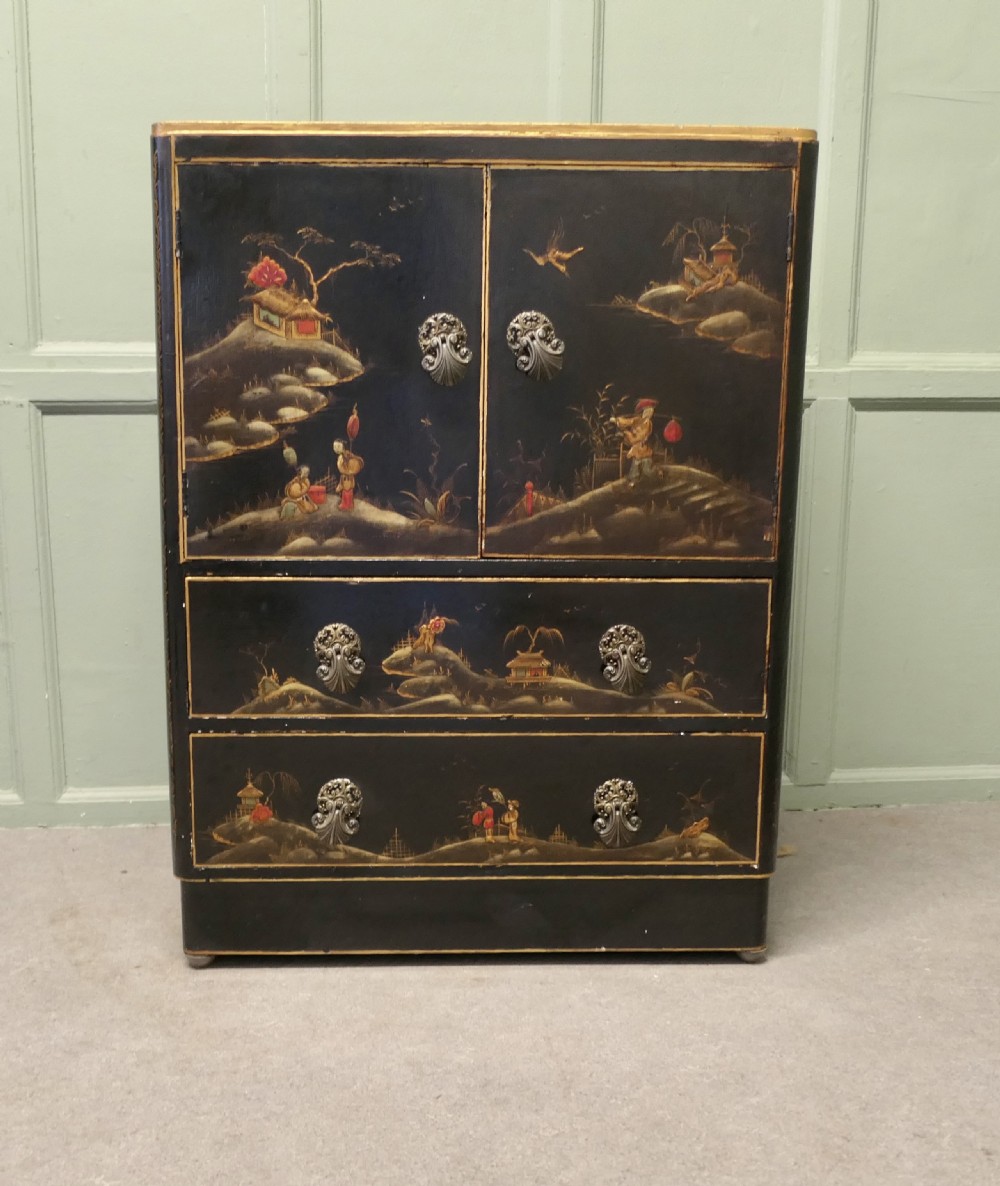 A black lacquered cupboard featuring hand-painted Chinoiserie landscape scenes, two upper doors, two lower drawers, and metal handles.