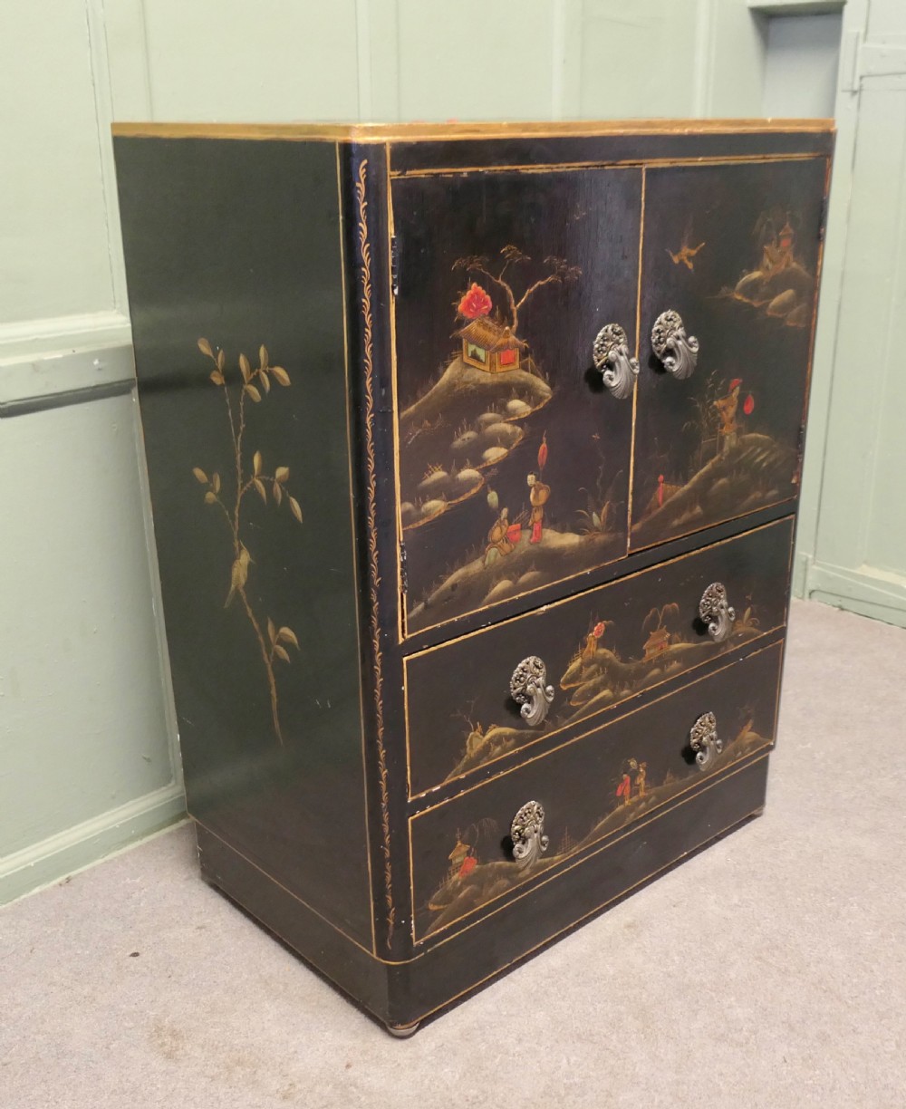 A black lacquered cupboard featuring hand-painted Chinoiserie landscape scenes, two upper doors, two lower drawers, and metal handles. View VI