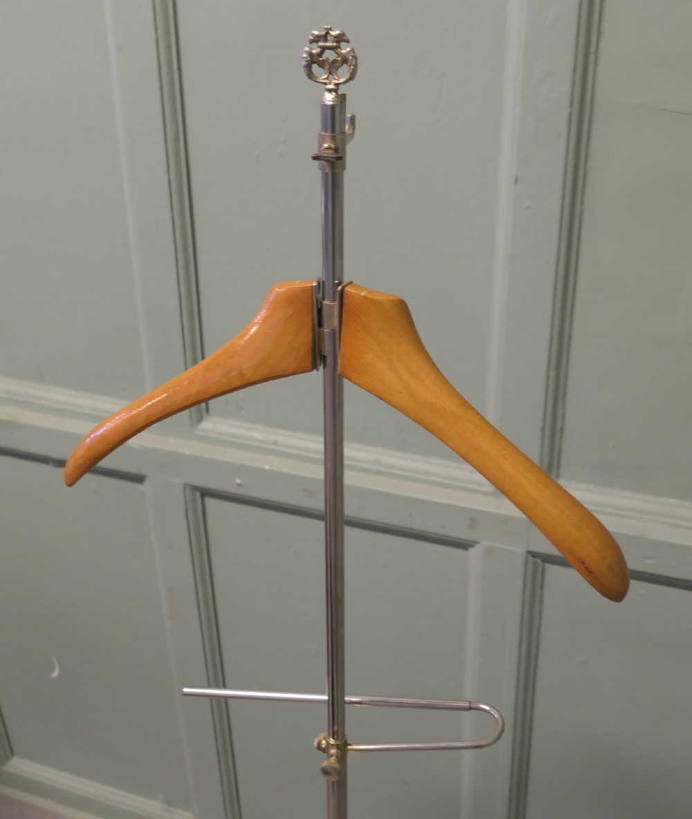 A freestanding French valet stand featuring a circular weighted chrome base, a central vertical chrome stem with trouser rail, and a contoured light beech wood hanger at the top. View II
