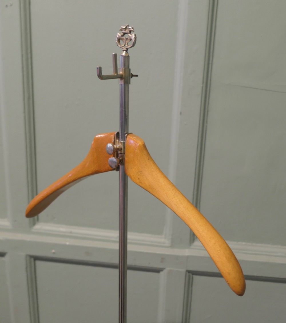 A freestanding French valet stand featuring a circular weighted chrome base, a central vertical chrome stem with trouser rail, and a contoured light beech wood hanger at the top. View III