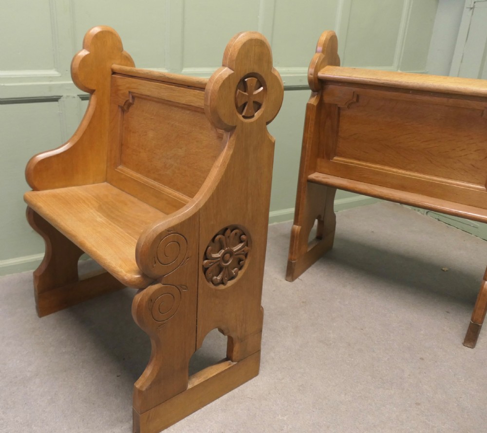 A pair of solid oak Arts and Crafts style hall chairs featuring shaped bench ends, fielded back panels, and gothic cut-outs. View III