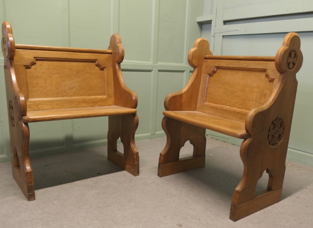 A pair of solid oak Arts and Crafts style hall chairs featuring shaped bench ends, fielded back panels, and gothic cut-outs. View VI