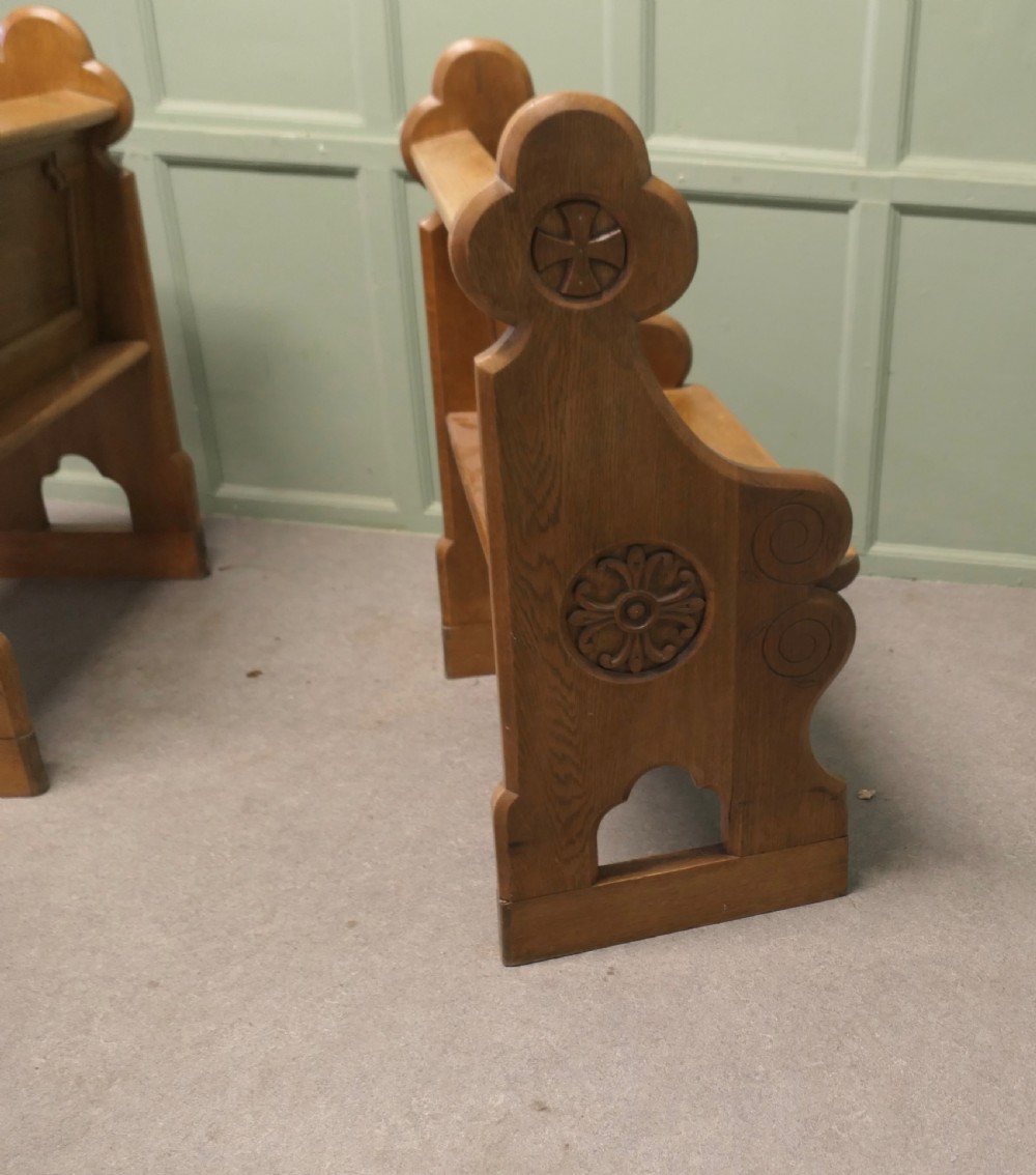 A pair of solid oak Arts and Crafts style hall chairs featuring shaped bench ends, fielded back panels, and gothic cut-outs. View VII