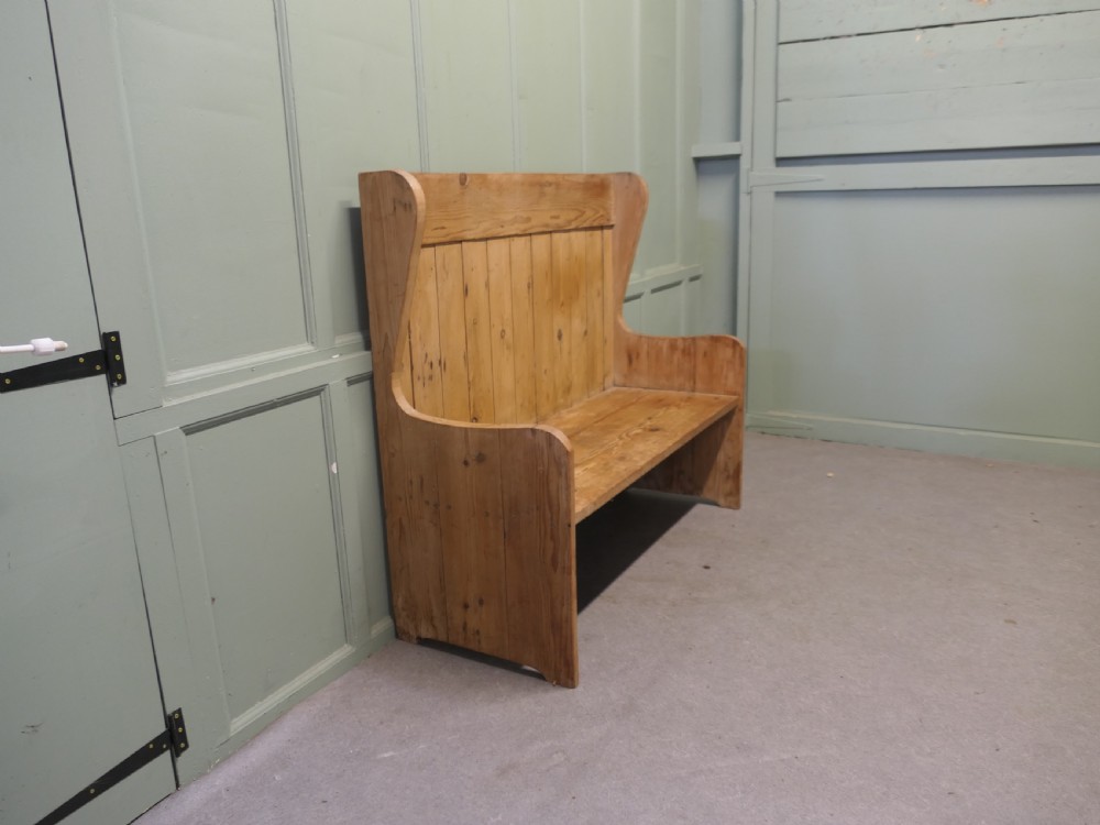 A high-back rustic pine settle bench featuring vertical planking and solid side armrests in a natural warm wood finish. View III