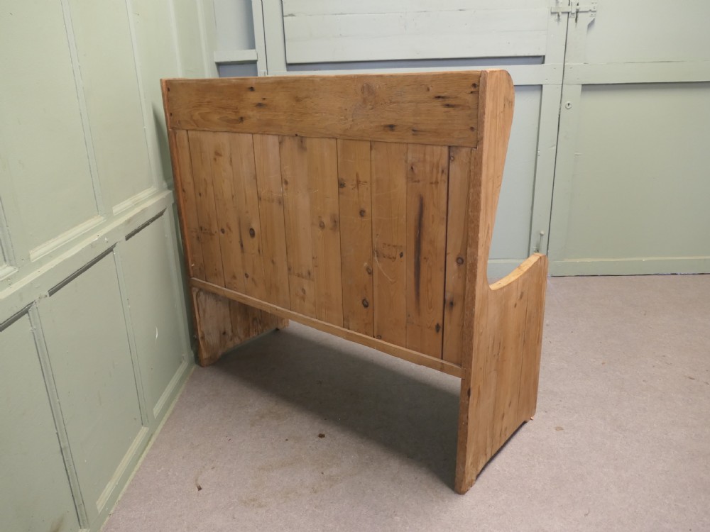 A high-back rustic pine settle bench featuring vertical planking and solid side armrests in a natural warm wood finish. View V