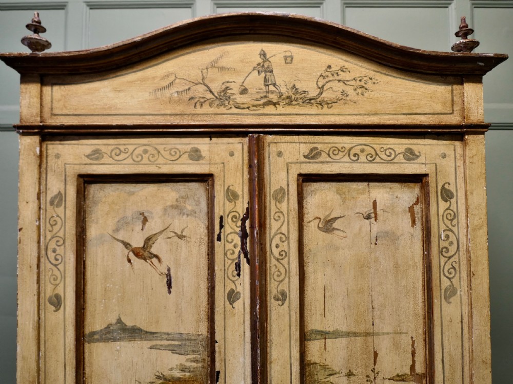 A tall, cream-painted antique cupboard featuring hand-painted Chinoiserie landscape scenes across two full-length doors and an arched pediment. View IV