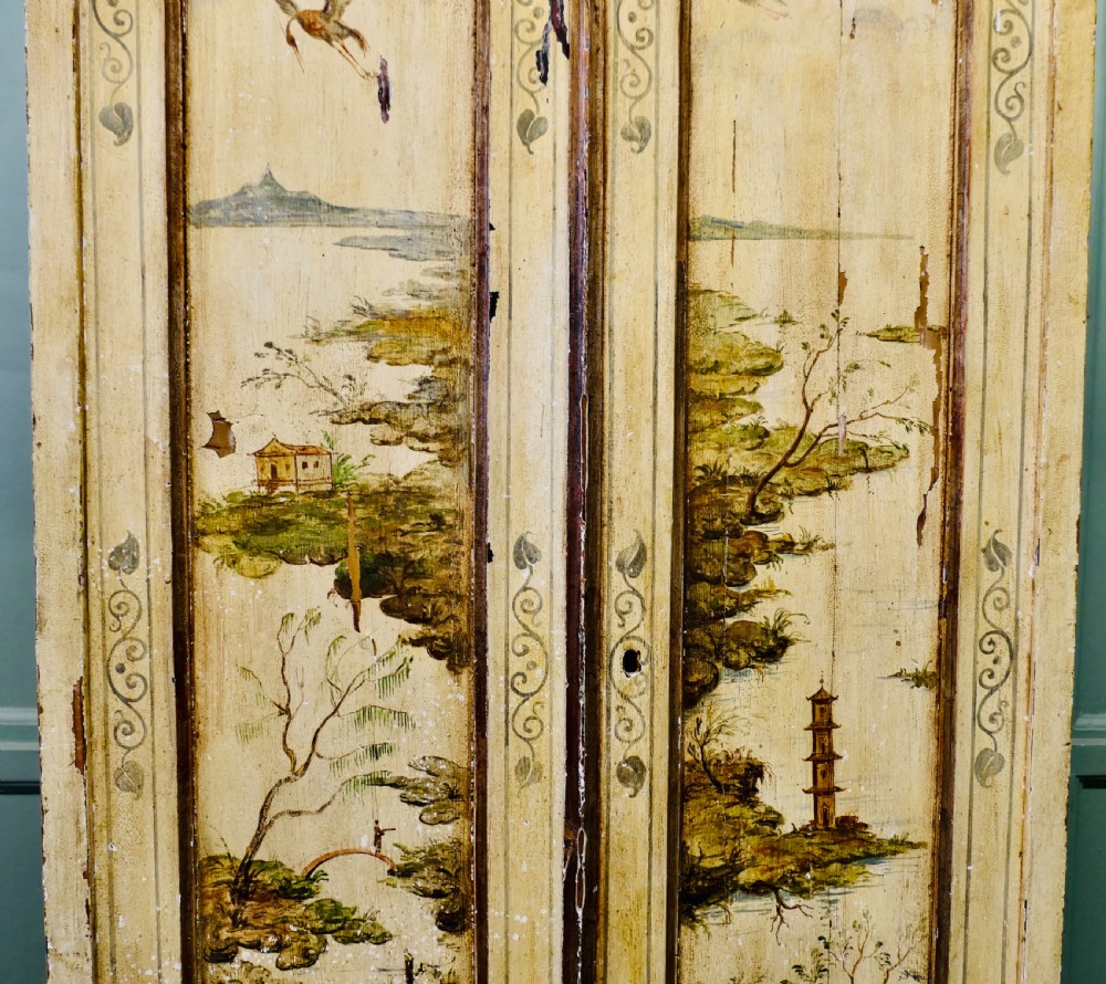A tall, cream-painted antique cupboard featuring hand-painted Chinoiserie landscape scenes across two full-length doors and an arched pediment. View V
