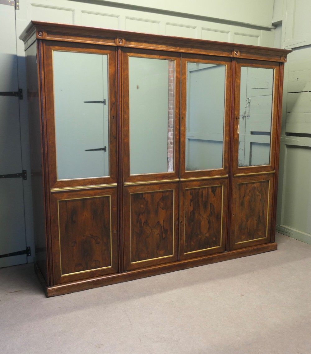 A nineteenth-century Regency rosewood four-door wardrobe with mirrored upper sections and brass stringing decoration. View II