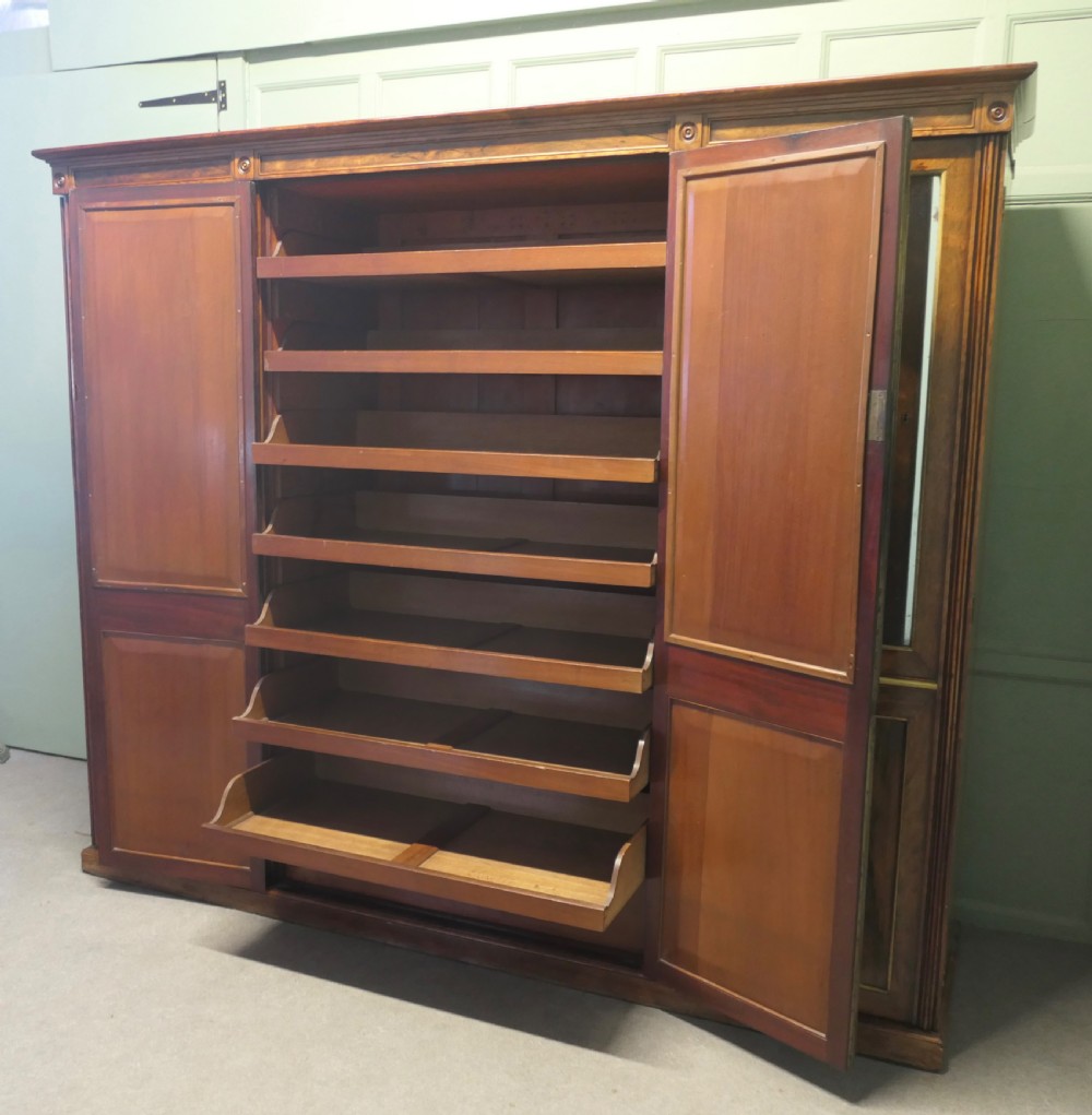 A nineteenth-century Regency rosewood four-door wardrobe with mirrored upper sections and brass stringing decoration. View V
