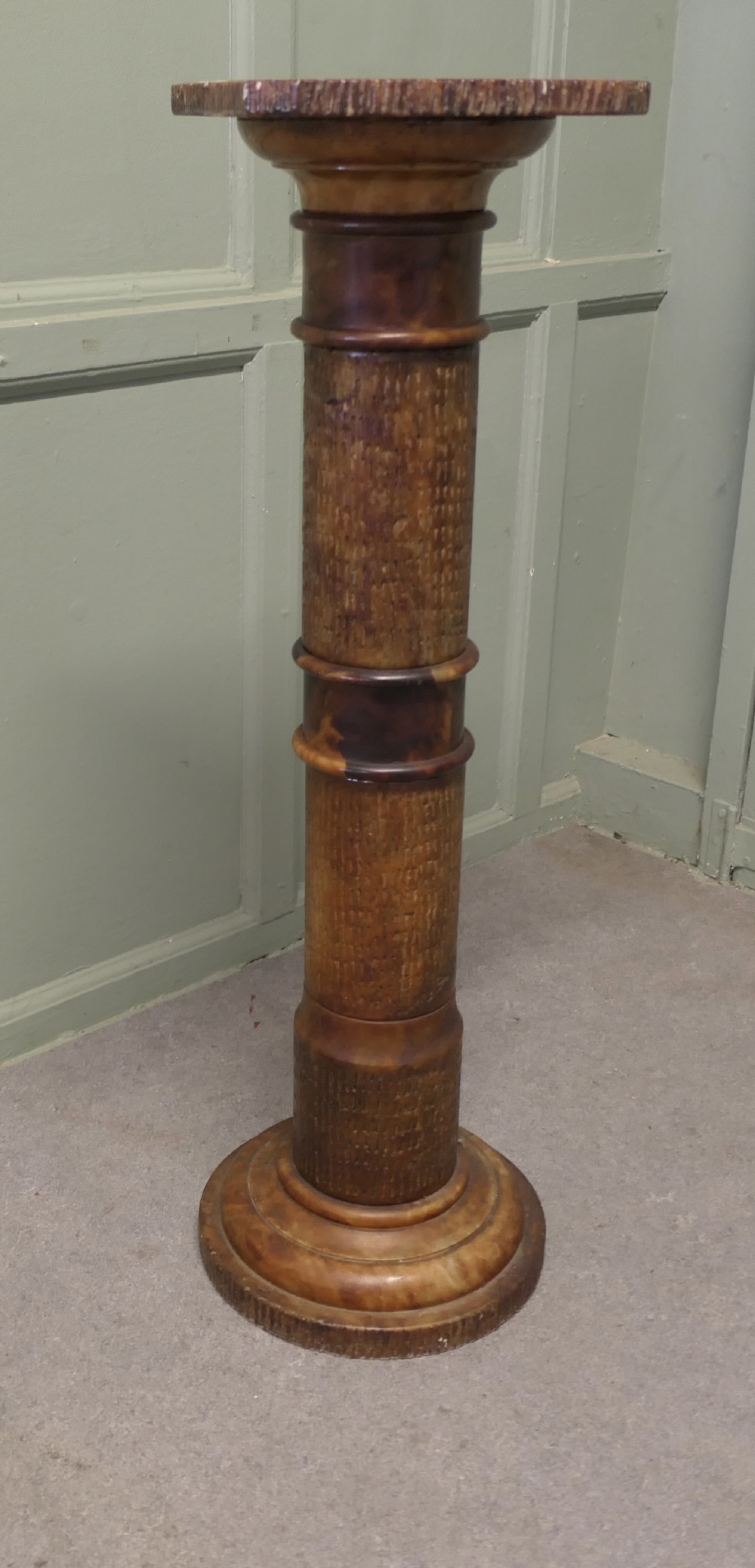 A tall honey-coloured marble pedestal column featuring a flat top surface, turned shaft with raised ring mouldings, and a heavy circular base.