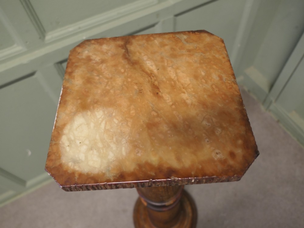A tall honey-coloured marble pedestal column featuring a flat top surface, turned shaft with raised ring mouldings, and a heavy circular base. View V