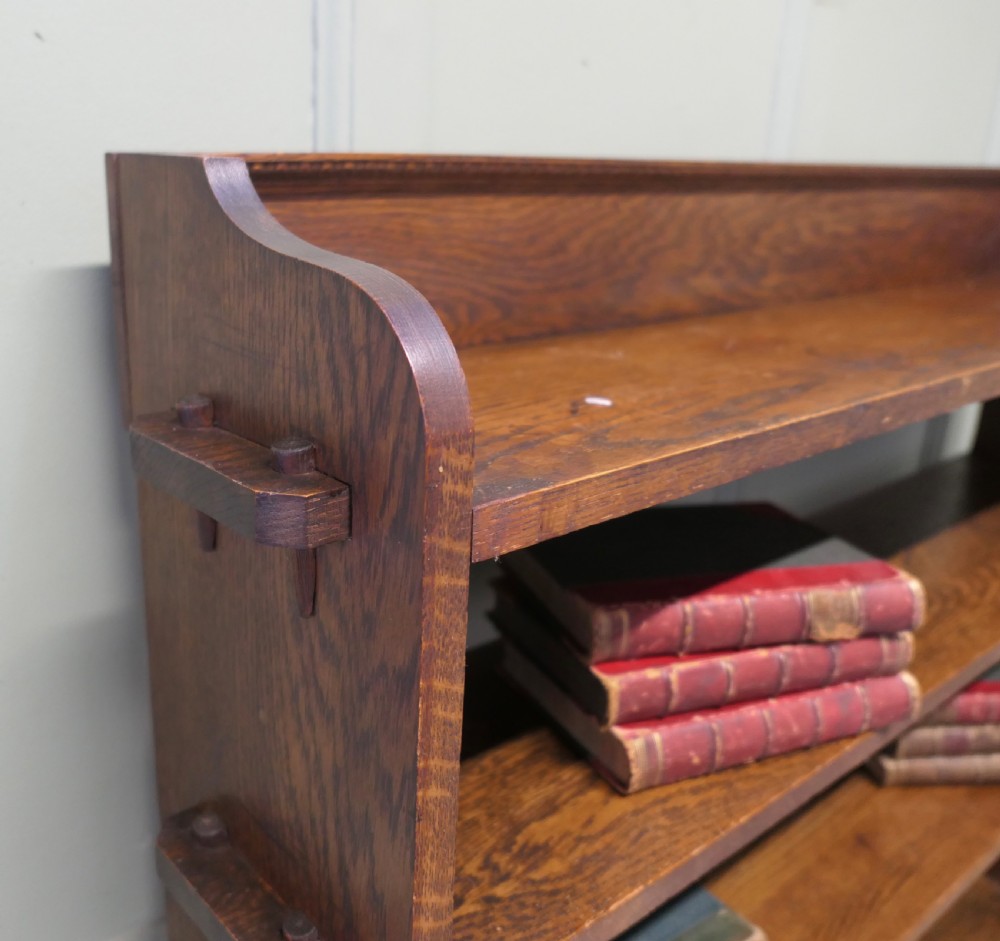 An Arts and Crafts oak bookcase featuring five open shelves with prominent exposed side tenons. View V