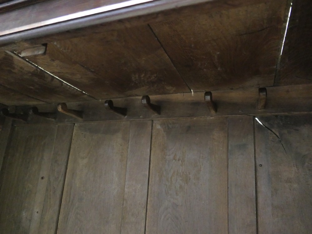 A tall dark Georgian oak housekeepers cupboard featuring two upper doors with arched fielded panels over a lower section with two drawers. View V