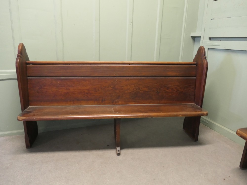 An antique Arts and Crafts pitch pine church pew featuring a solid panelled back and shaped bench ends. View III