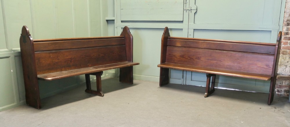 An antique Arts and Crafts pitch pine church pew featuring a solid panelled back and shaped bench ends. View IV