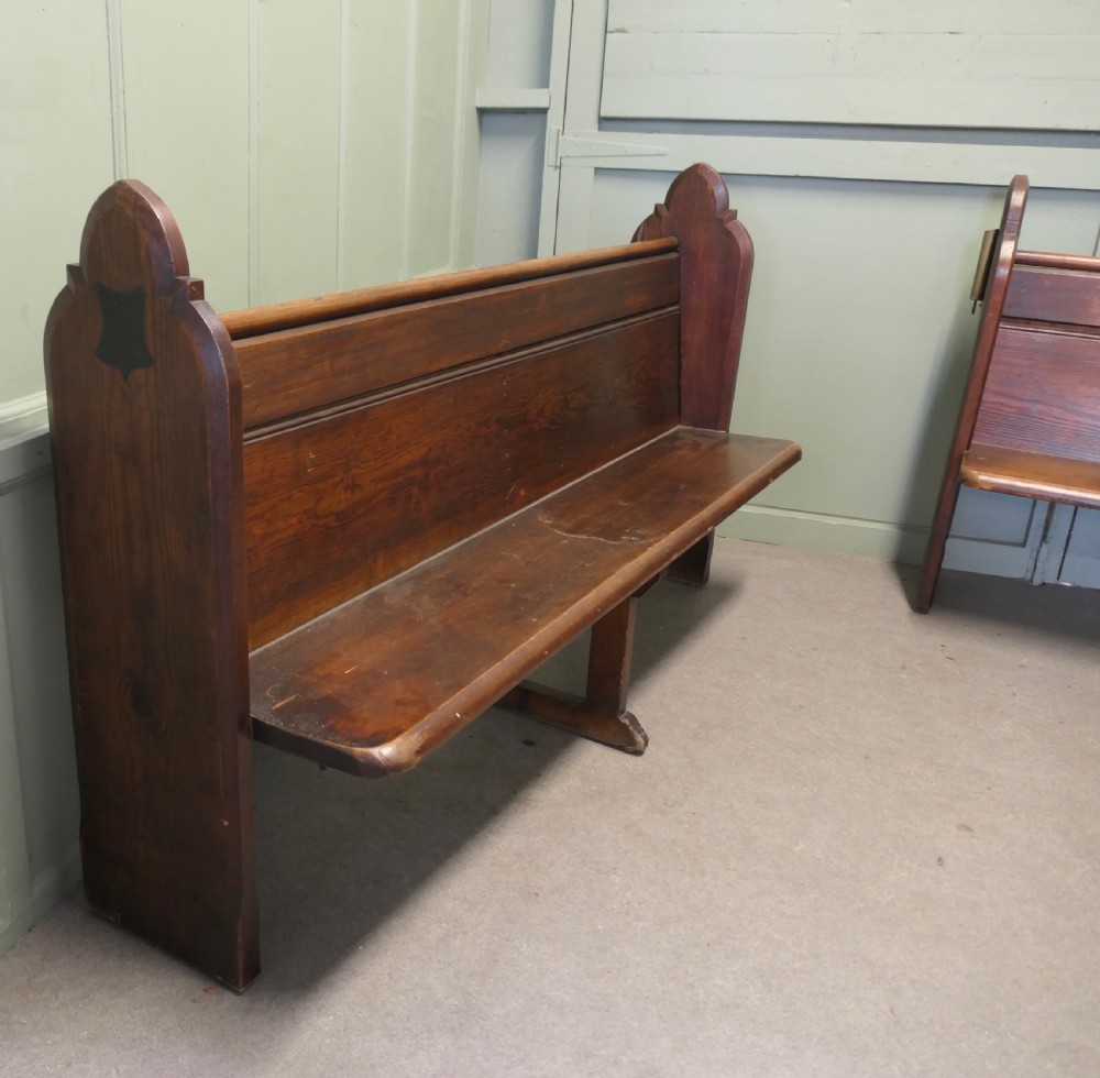 An antique Arts and Crafts pitch pine church pew featuring a solid panelled back and shaped bench ends. View V