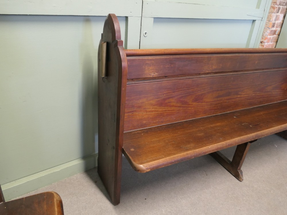 An antique Arts and Crafts pitch pine church pew featuring a solid panelled back and shaped bench ends. View VI