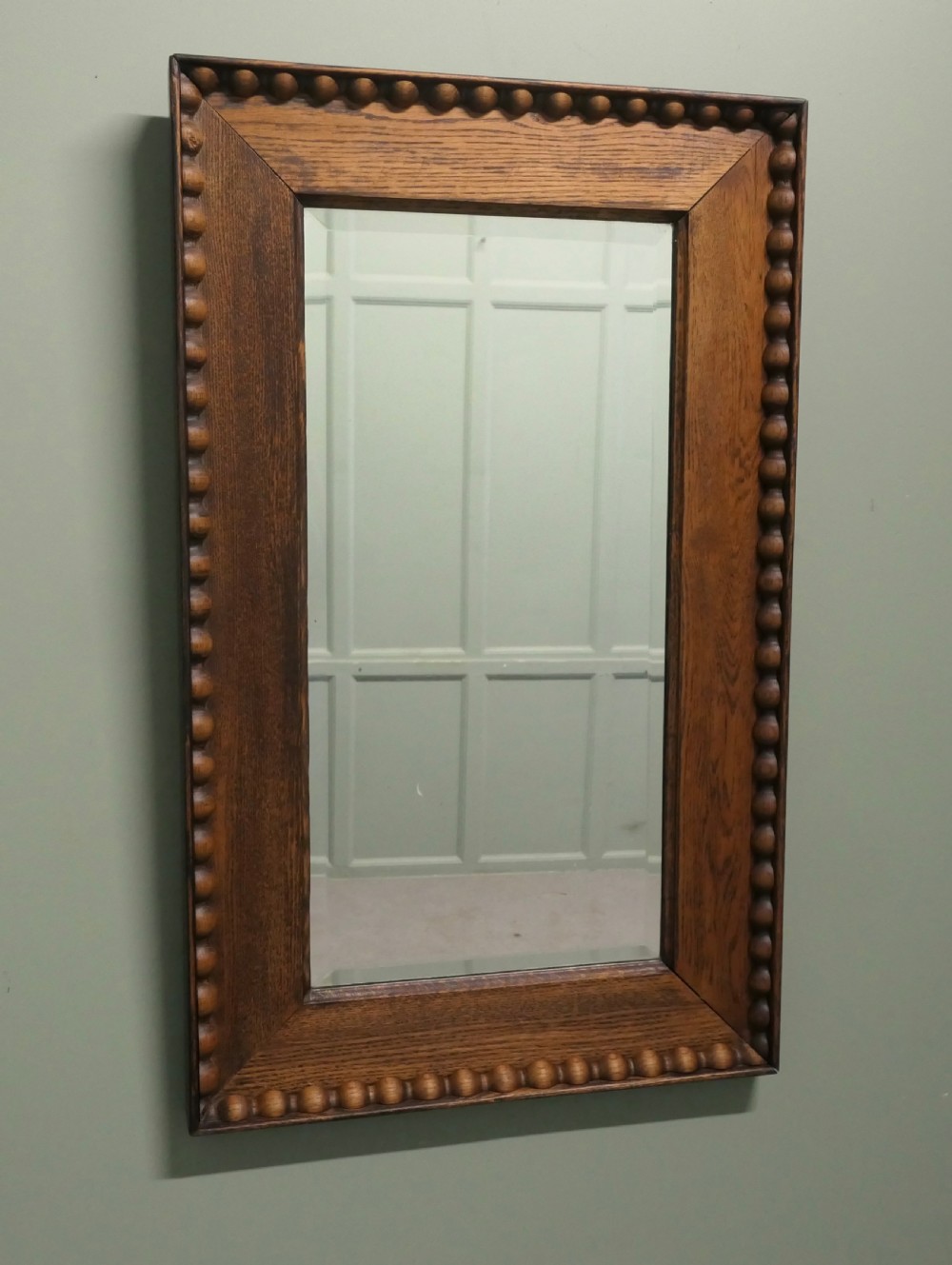 A rectangular Victorian golden oak wall mirror featuring a carved beaded outer border and mitred frame corners.