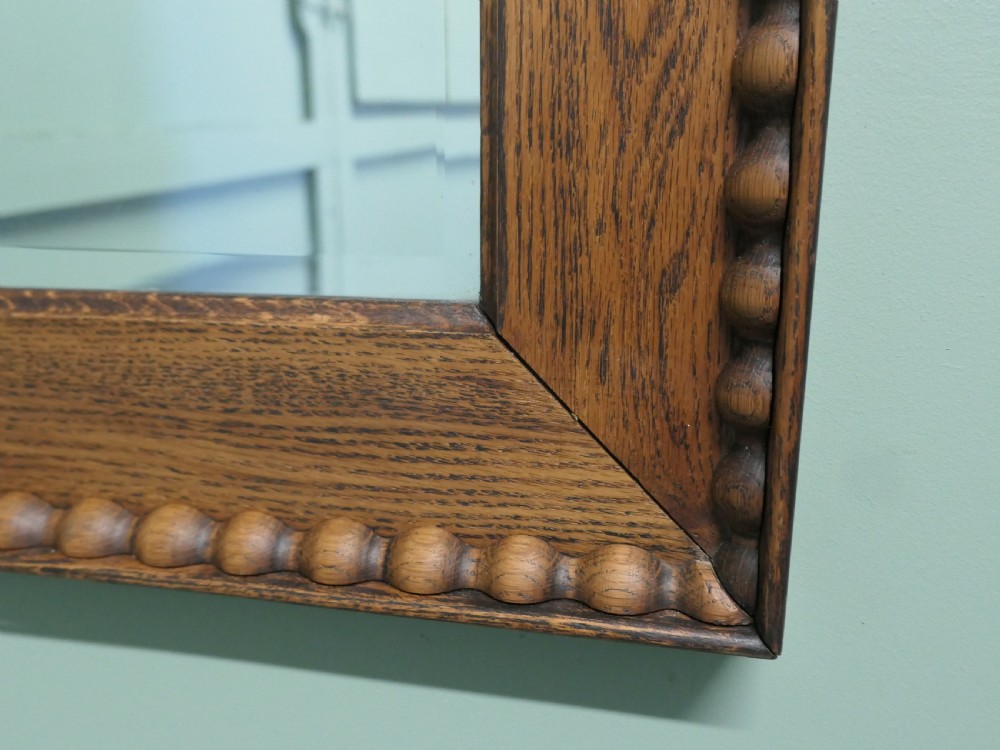 A rectangular Victorian golden oak wall mirror featuring a carved beaded outer border and mitred frame corners. View V