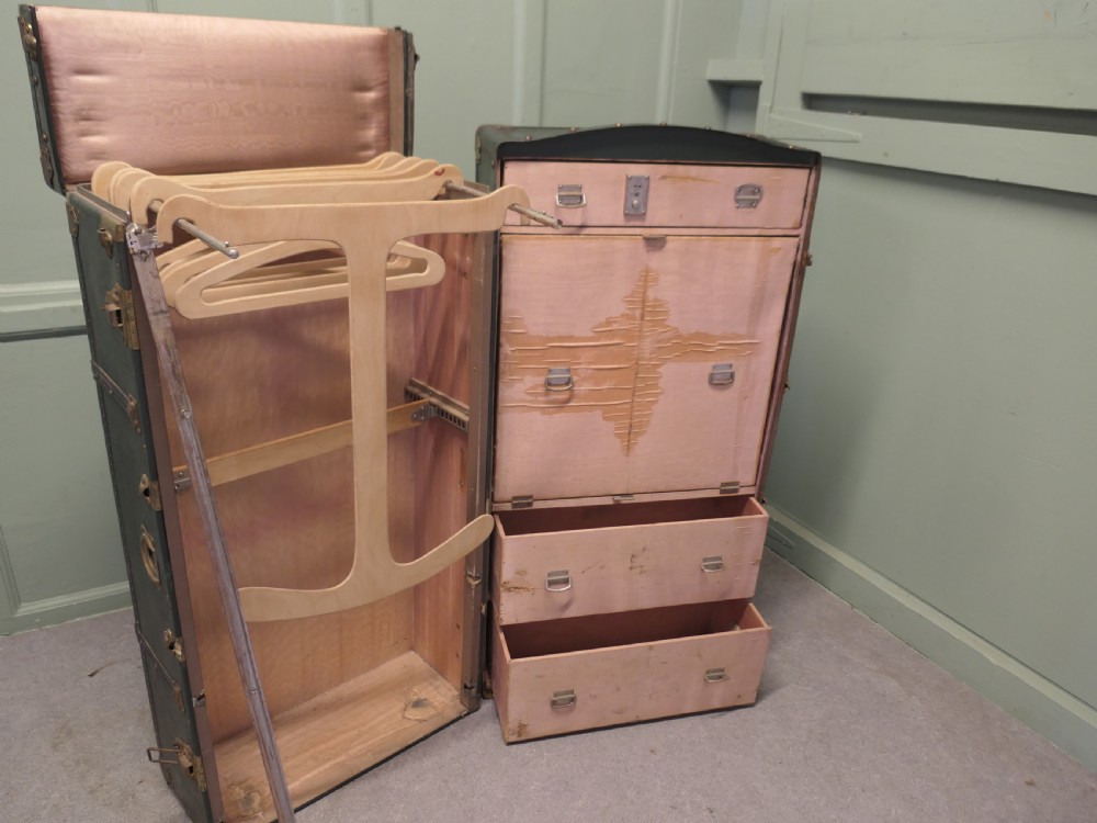 A tall, upright dark green French steamer wardrobe trunk with brass corner braces, studded trim, and side leather handles. View IV
