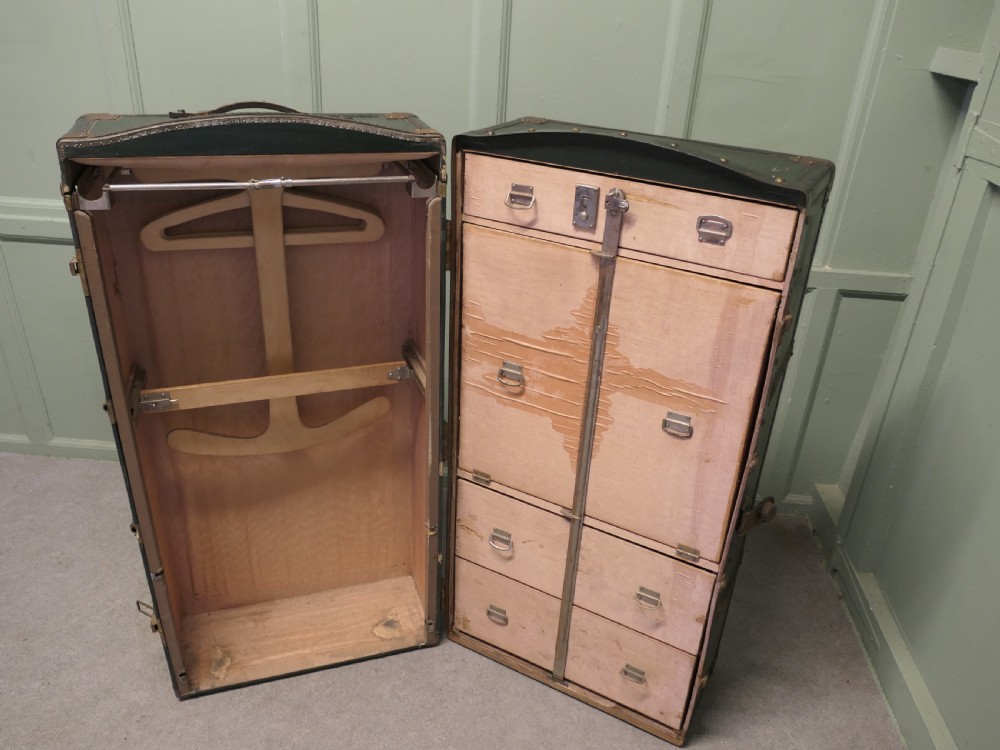 A tall, upright dark green French steamer wardrobe trunk with brass corner braces, studded trim, and side leather handles. View V