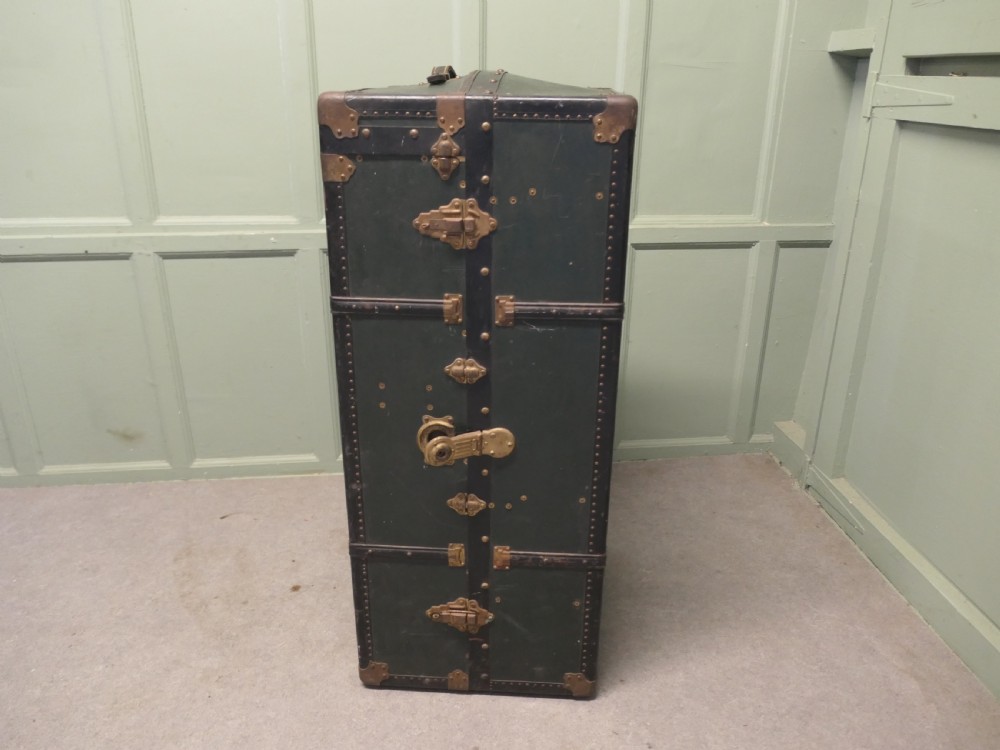 A tall, upright dark green French steamer wardrobe trunk with brass corner braces, studded trim, and side leather handles. View VI